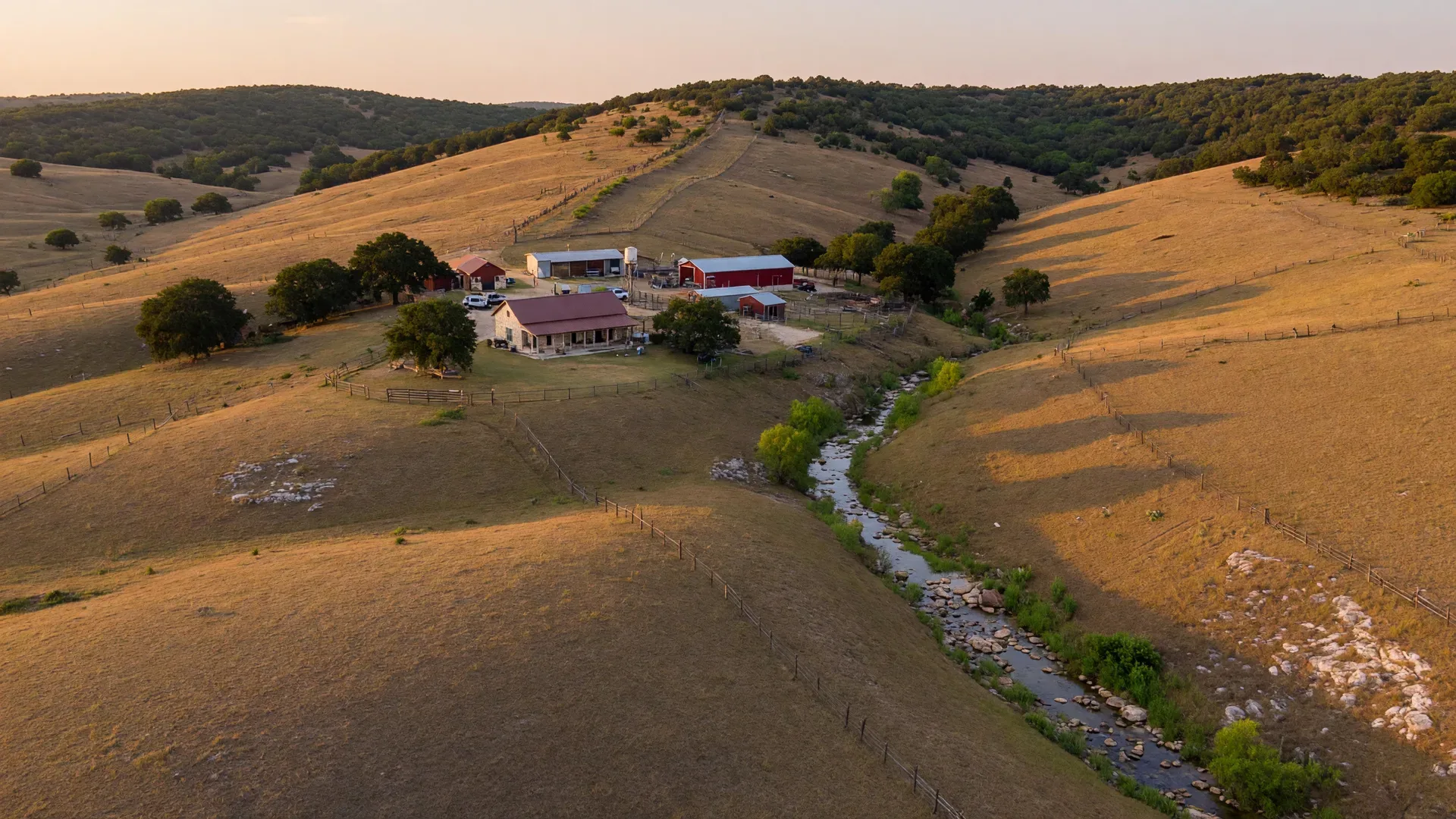 Aerial view of a Texas Hill Country property with pasture, oak trees, and homestead