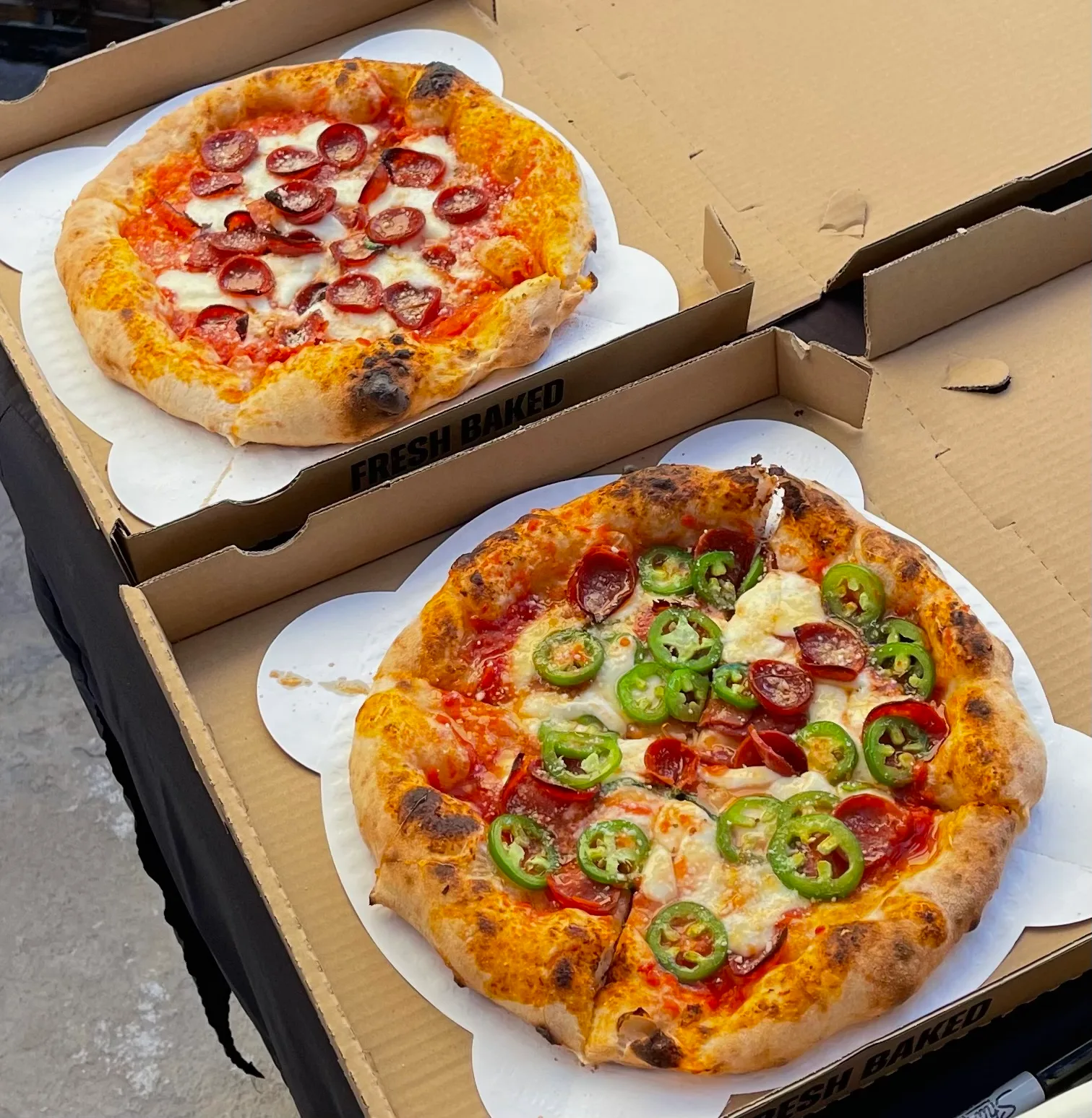 Two artisan pizzas in boxes: classic pepperoni on top and pepperoni with jalapeño for the Sweet Heat below