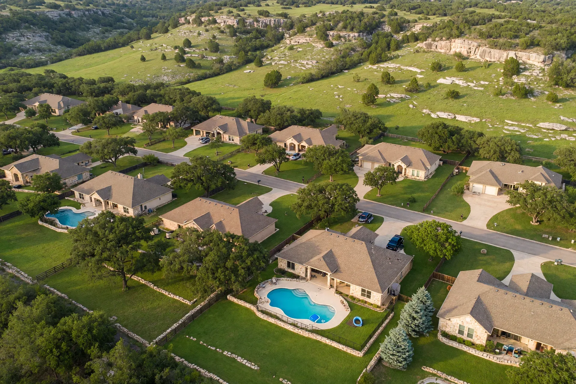Aerial view of a Texas Hill Country neighborhood with homes and pool