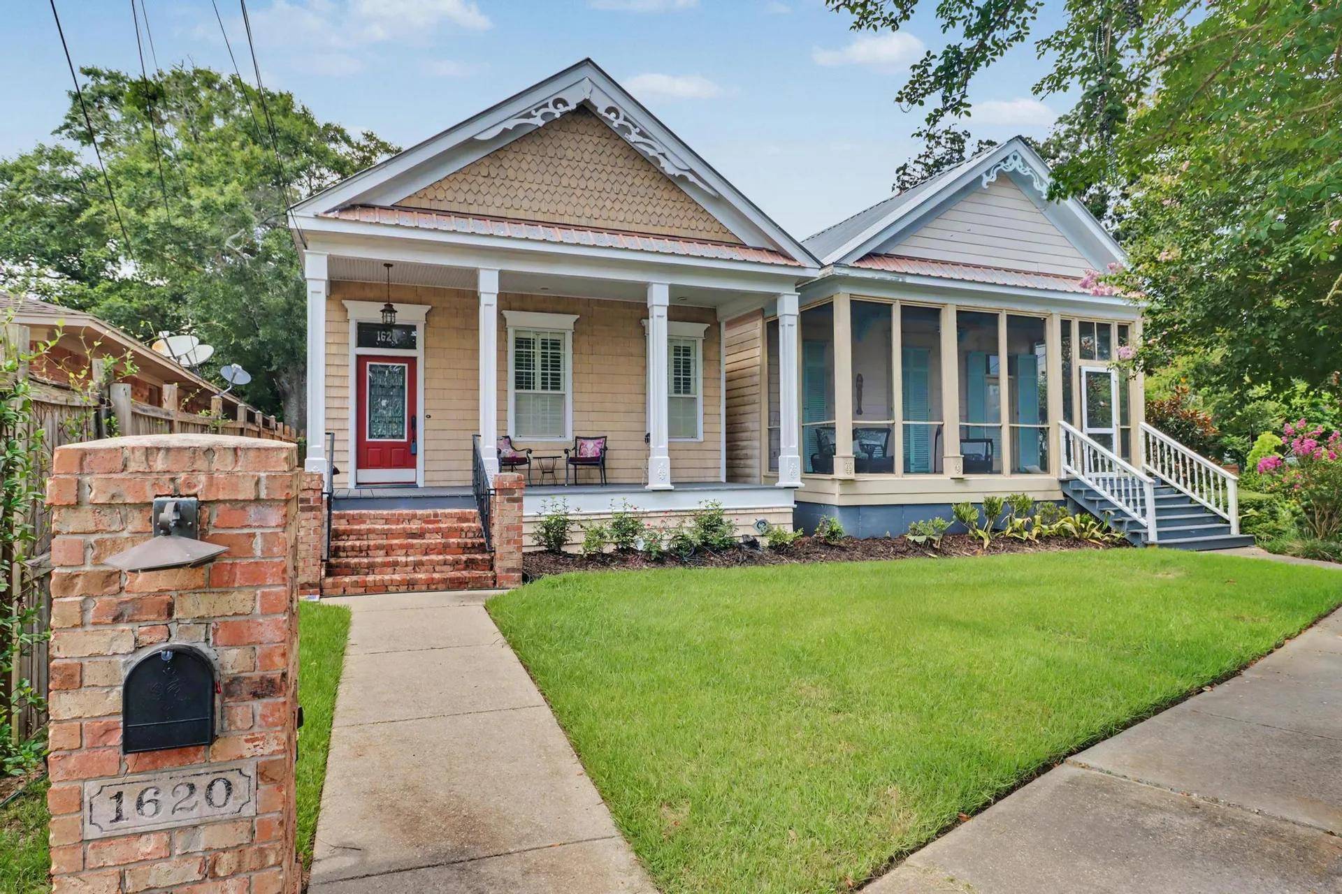 Exterior front view with front porch, screened side porch, and gingerbread trim
