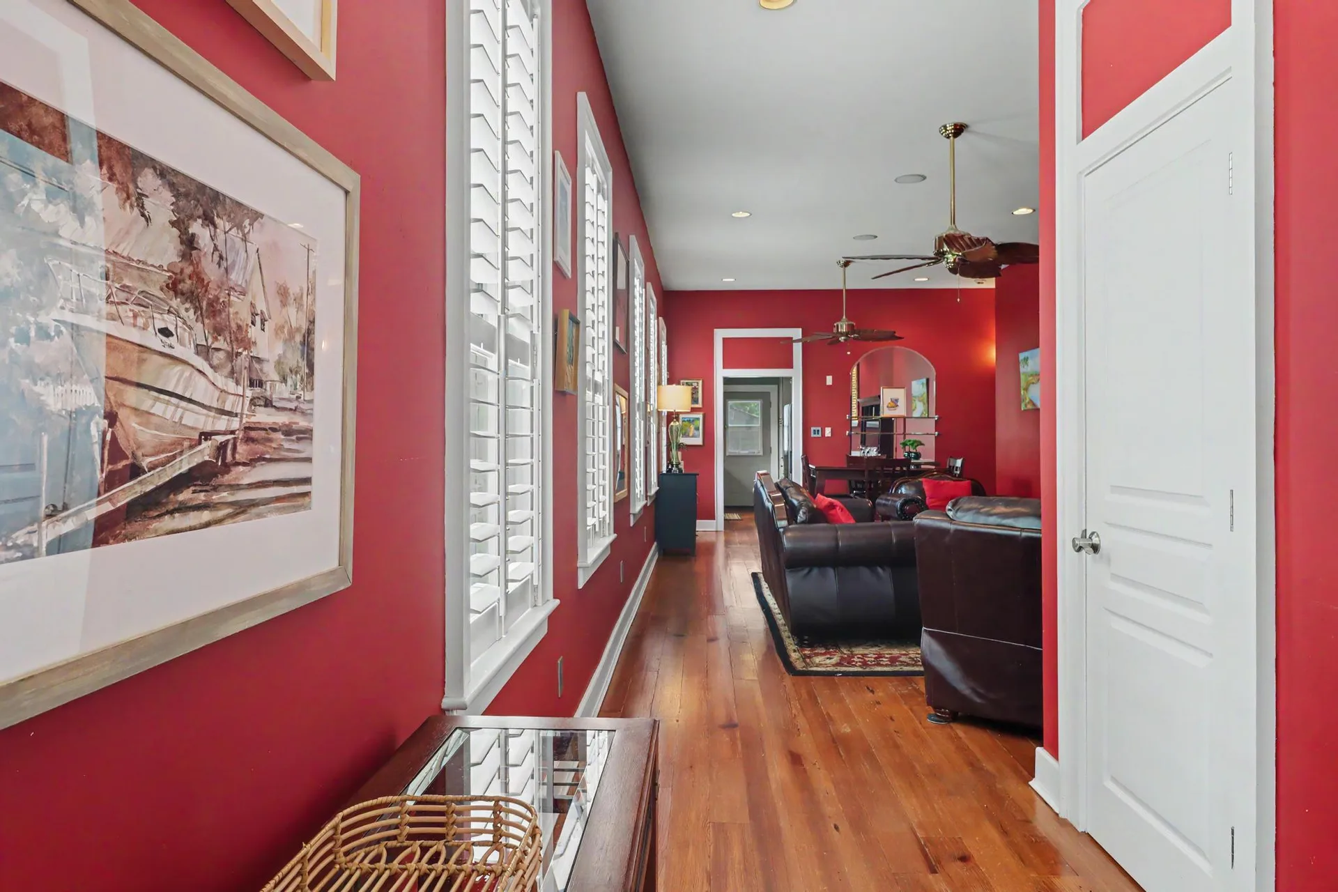 Hallway looking into the living room with red walls and heart pine flooring