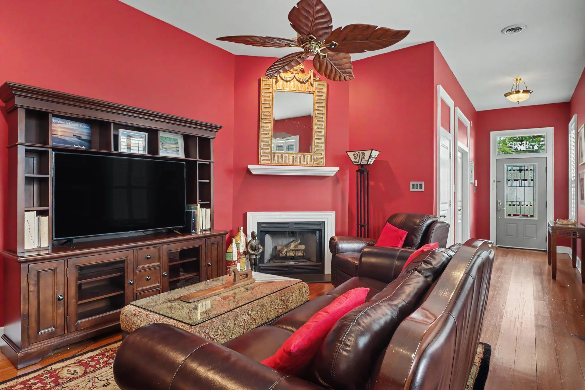Living room with corner fireplace, red walls, and heart pine floors