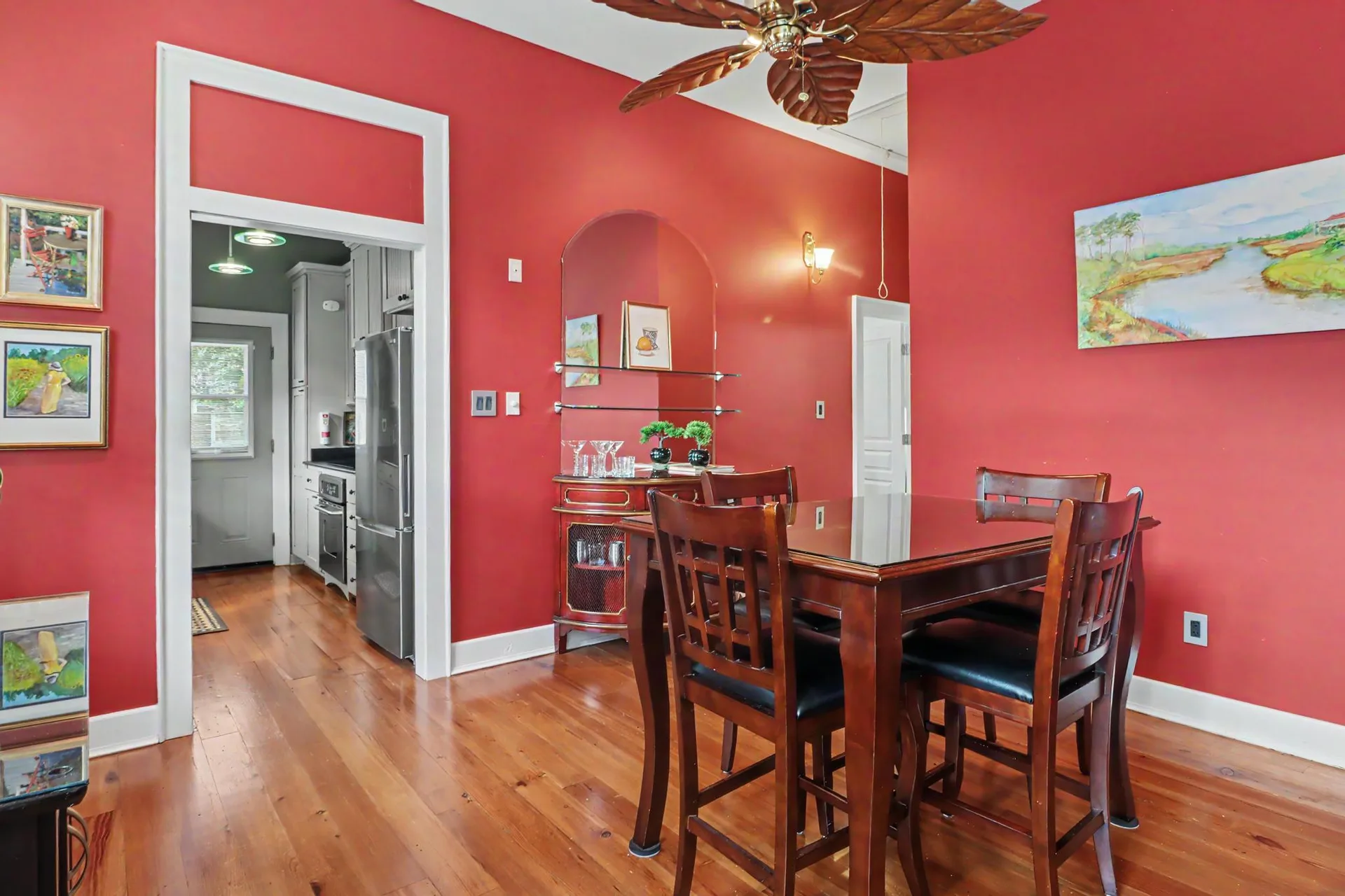 Dining room with bright red walls, high ceilings, and heart pine flooring