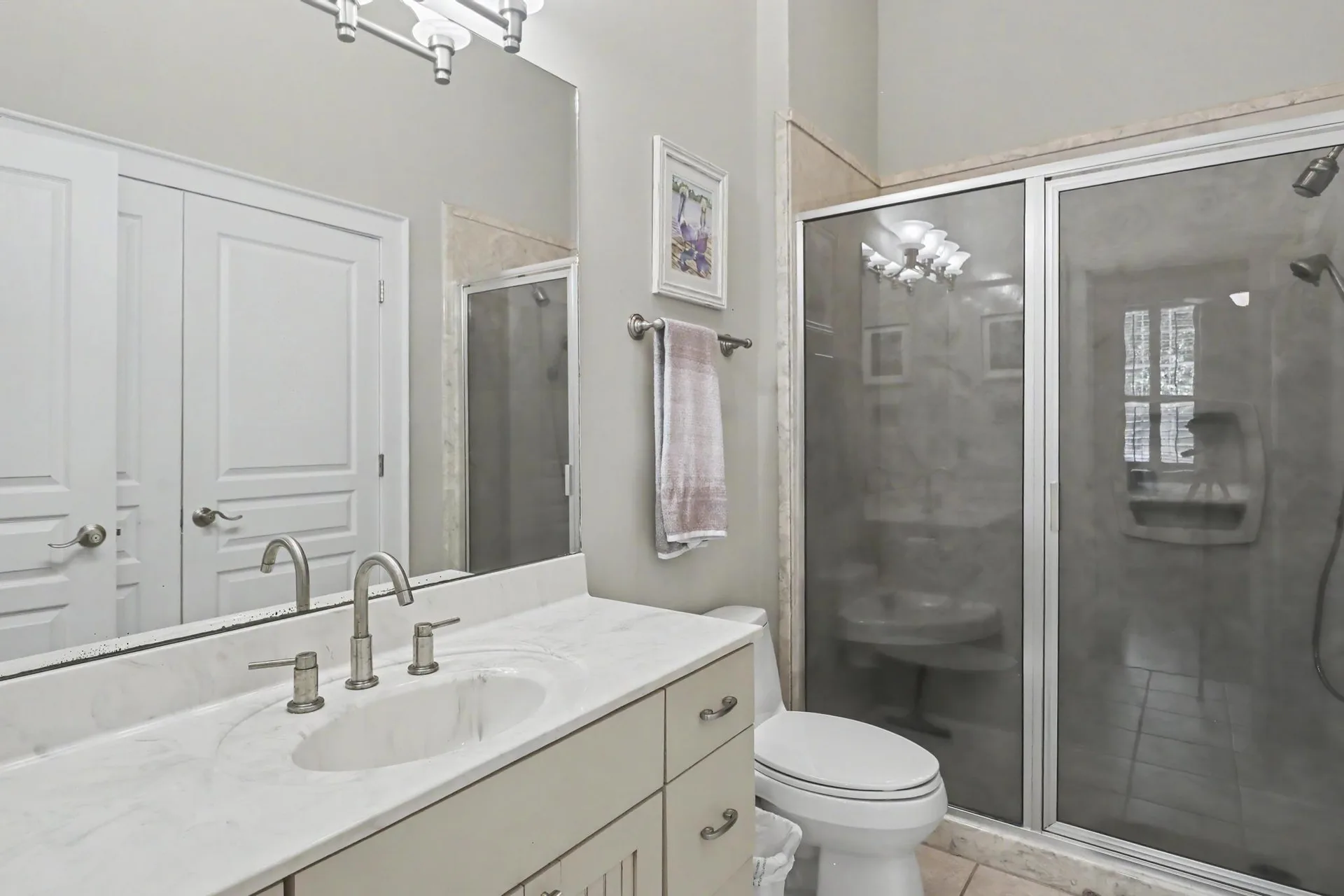 Bathroom with vanity, large wall mirror, and walk-in shower with sliding glass doors