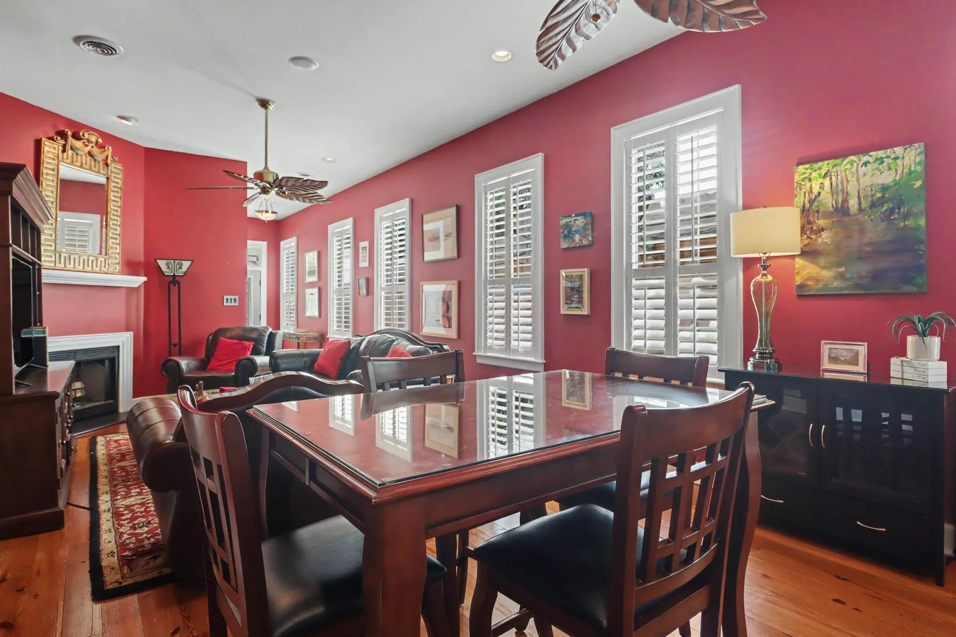 The open living and dining room at 1620 2nd Street with heart pine floors, a corner fireplace, and plantation shutters