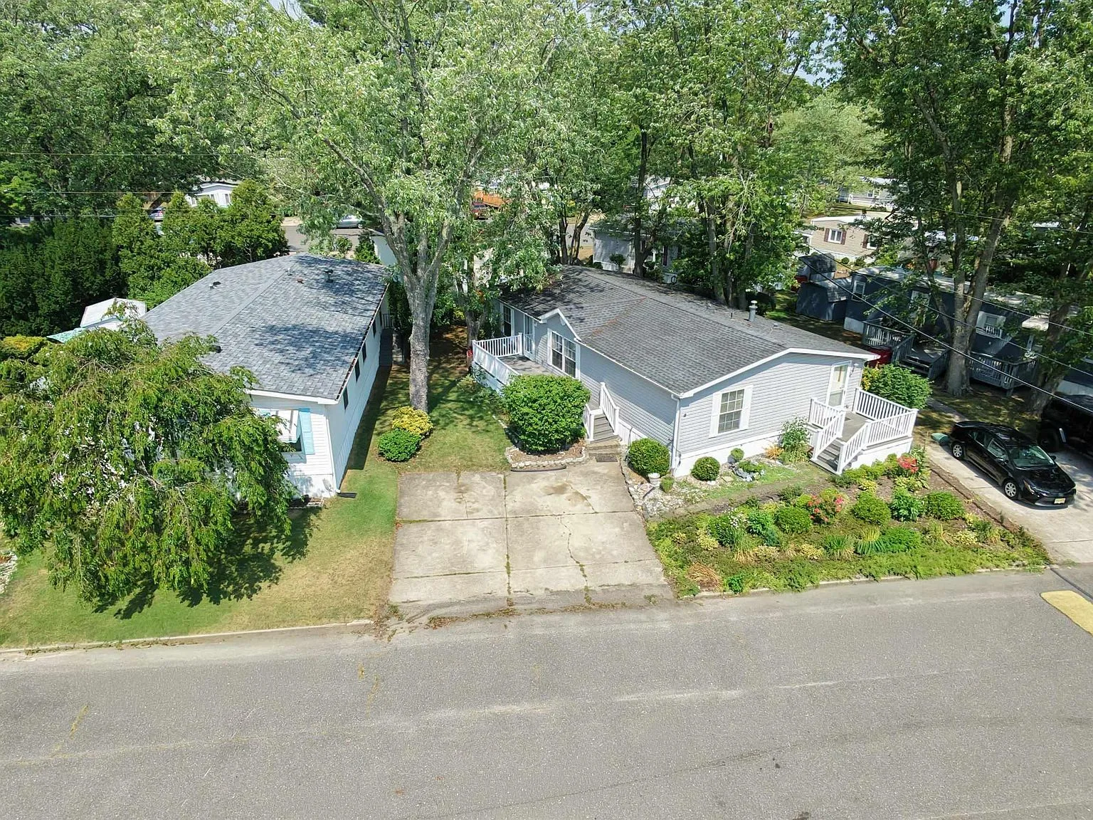 Aerial drone view of the manufactured home at 2528 Tilton Rd. Lot #48, showing the property, deck, and surrounding community
