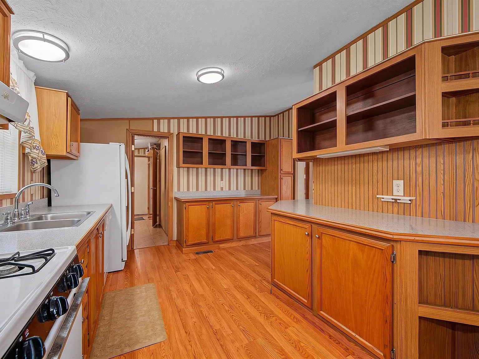 Wide-angle kitchen showing wood-grain cabinets and plank flooring