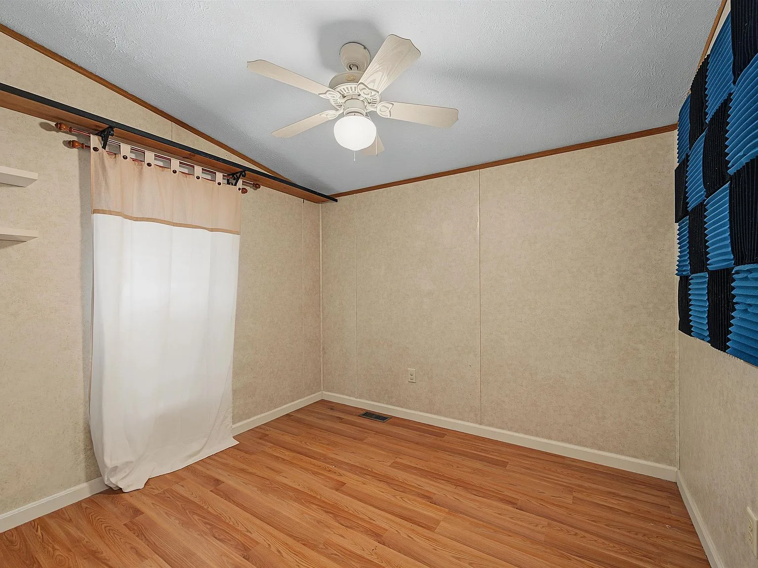 Secondary bedroom with laminate flooring and beige paneling