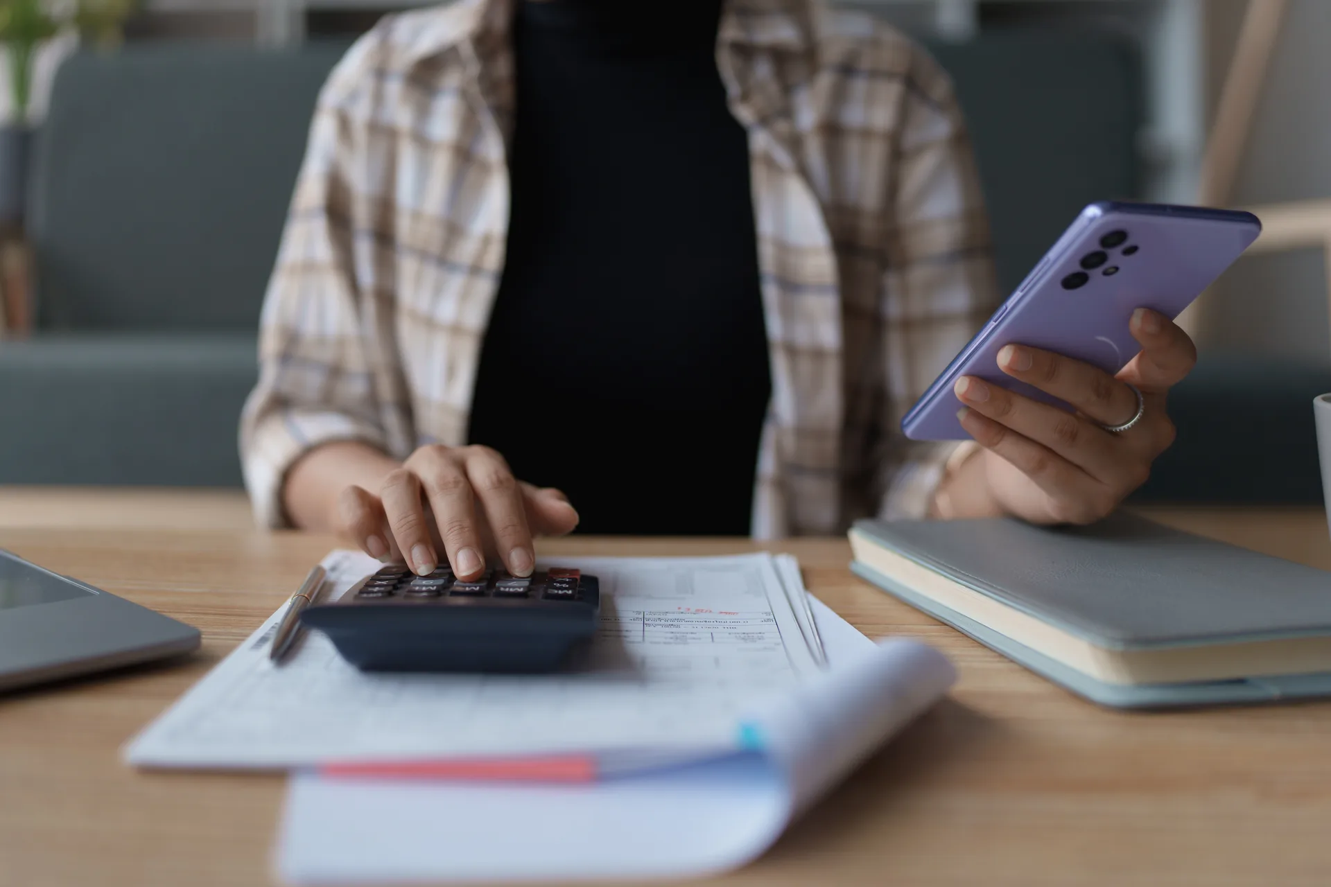Homeowner reviewing financial documents at a wooden desk with calculator and smartphone, illustrating the hidden costs of instant cash offers