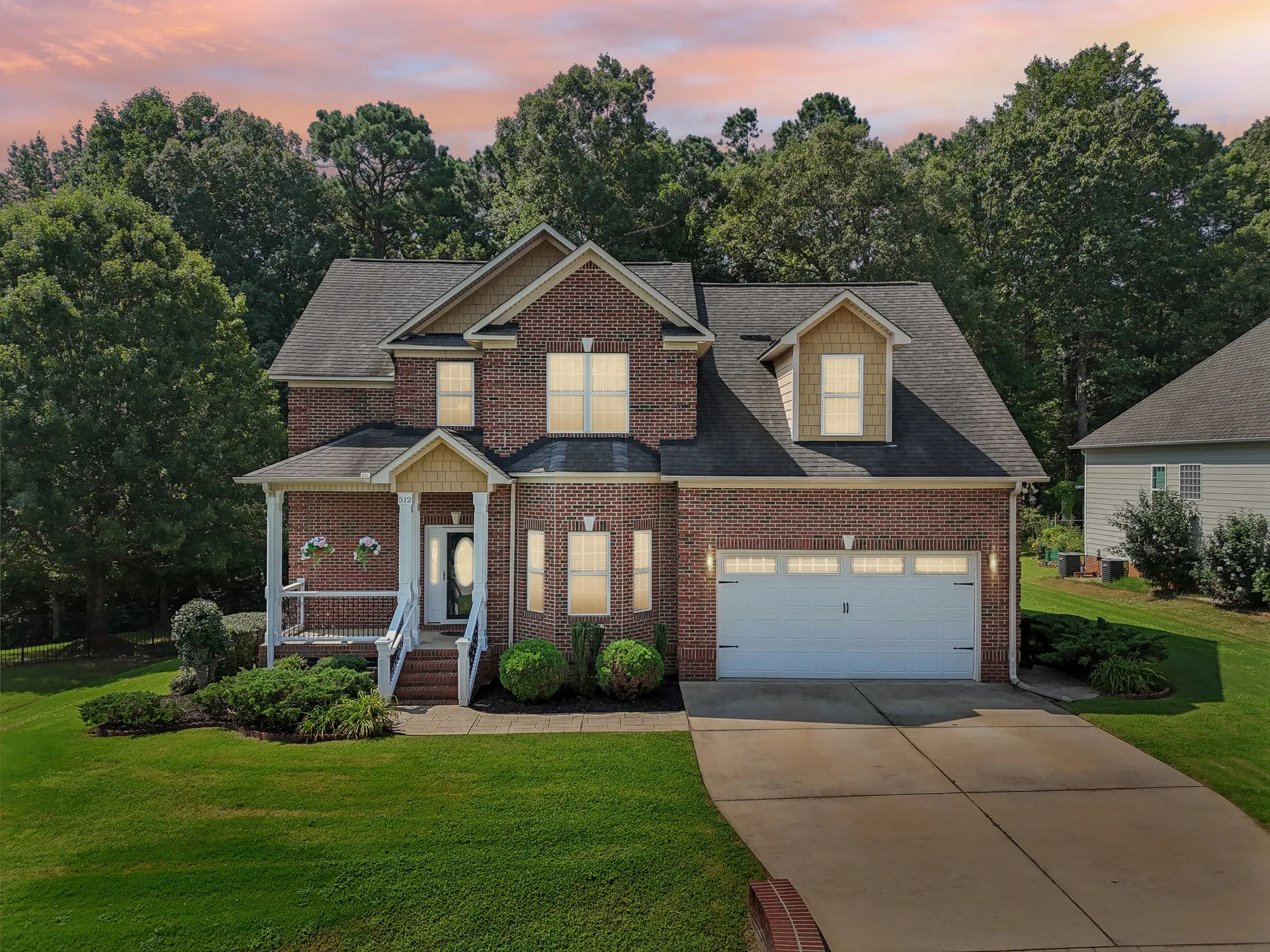 Twilight brick home exterior with warm window glow and sunset sky, used as a call-to-action banner background