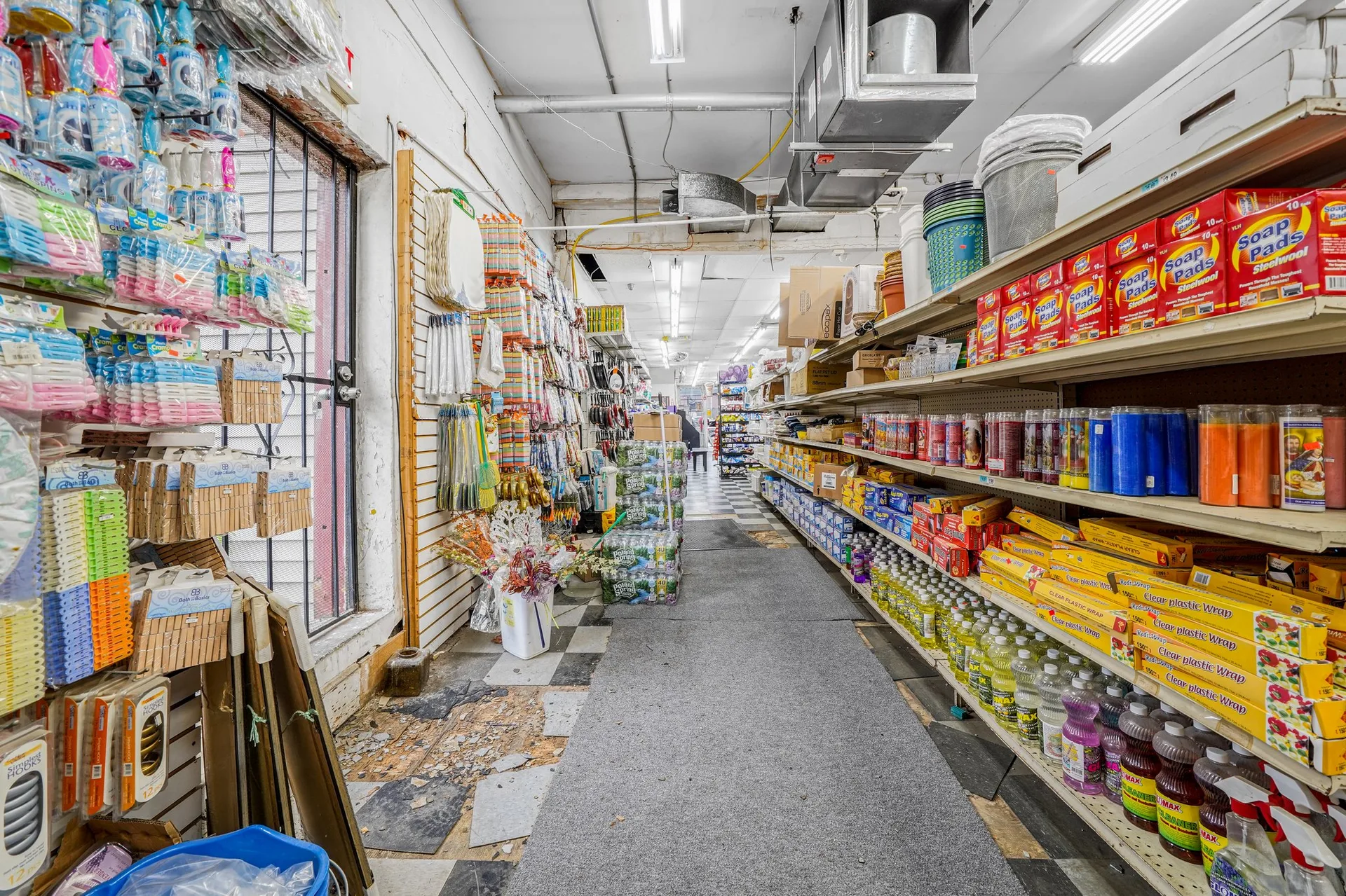 Narrow aisle perspective with snack foods, household goods, and commercial shelving