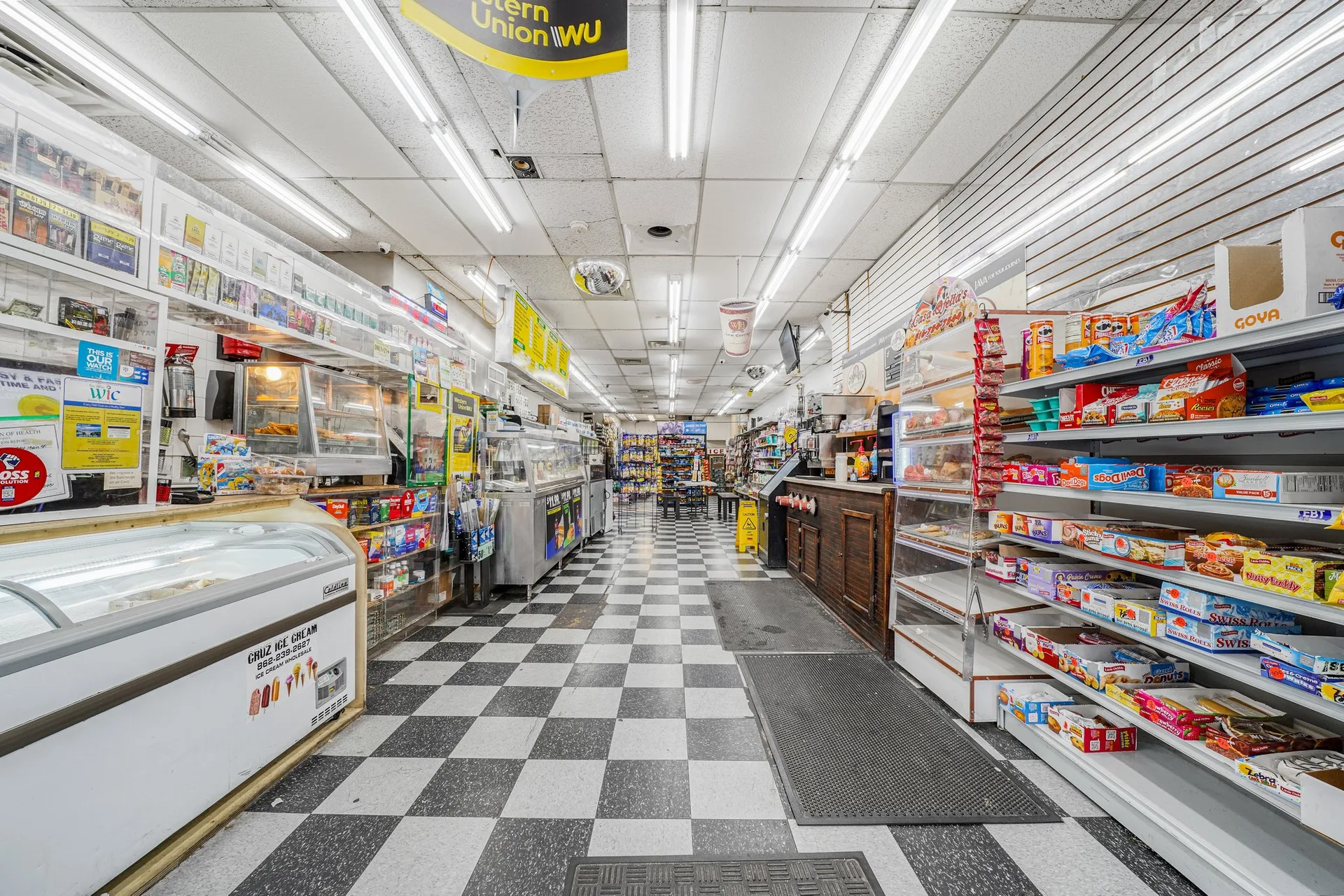 Supermarket retail space with refrigerated display cases, dry goods shelving, and condiment stations
