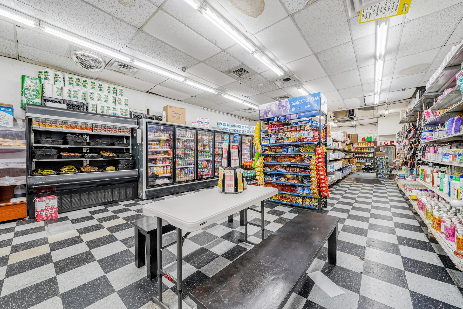 Interior retail space with multiple refrigerated units, shelving, and central seating
