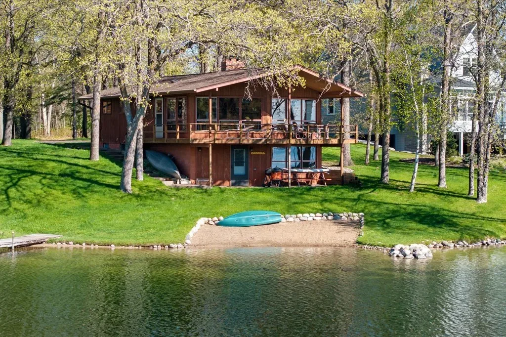Exterior lakefront view of back of property with deck, dock, and small beach area