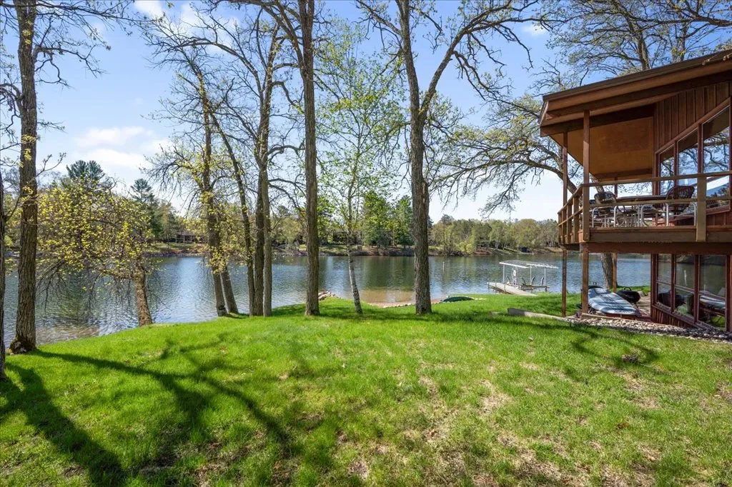 Backyard and lakefront view with wood siding home and furnished deck