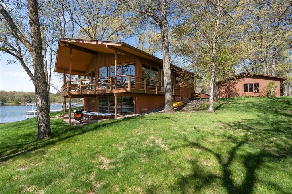 A-frame style home exterior with elevated deck and dappled tree shadows