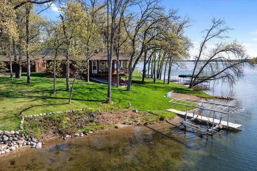 Backyard shot with rock garden, wooden deck, and boat dock on the lake