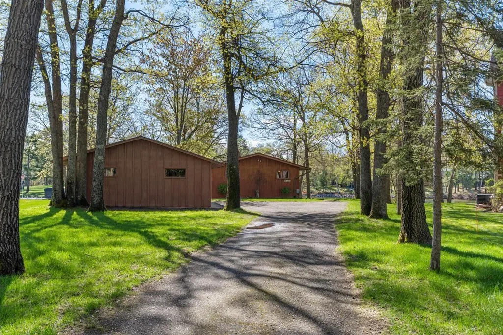 Backyard shot with two detached wooden outbuildings and grassy lawn