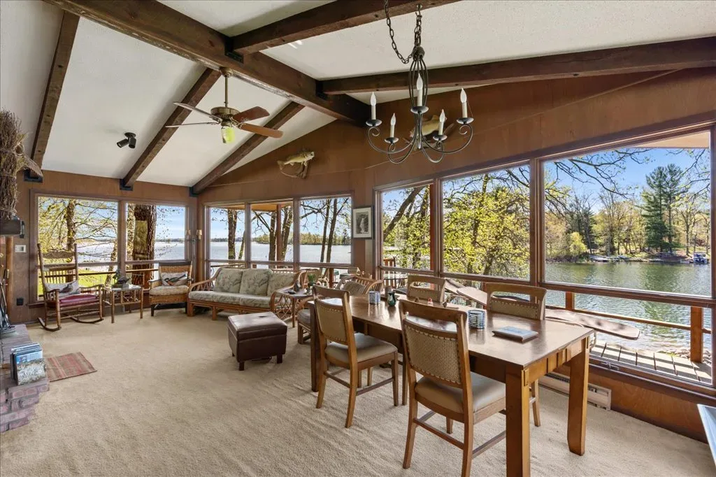 Sunroom and living area with vaulted wood ceiling beams, large windows, and lake views