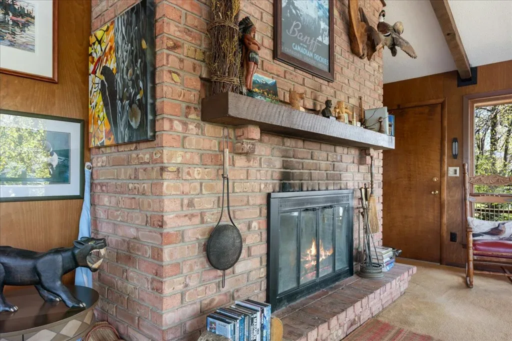 Rustic living room with red brick fireplace and wood-paneled walls