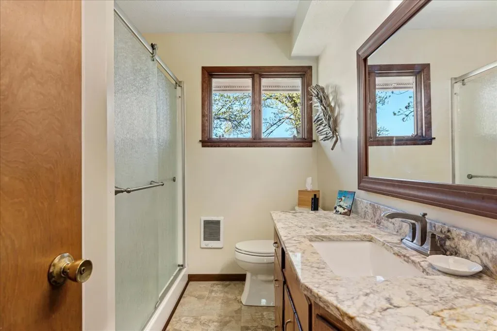 Bathroom with granite-style countertop and wooden vanity mirror frame