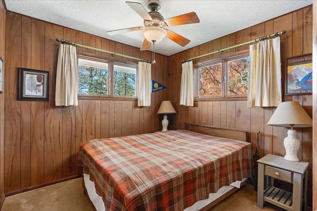 Rustic bedroom with wood-paneled walls and natural daylight