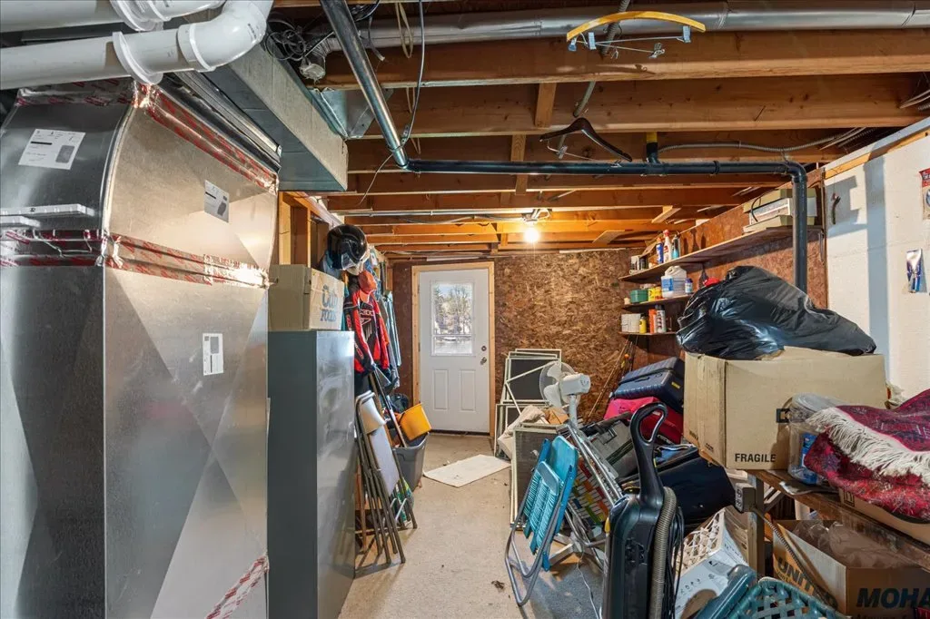 Unfinished basement storage area with exposed joists and concrete floor