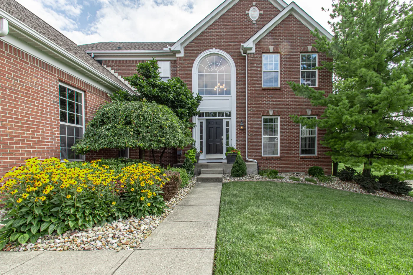 Front entrance with arched window and landscaped walkway