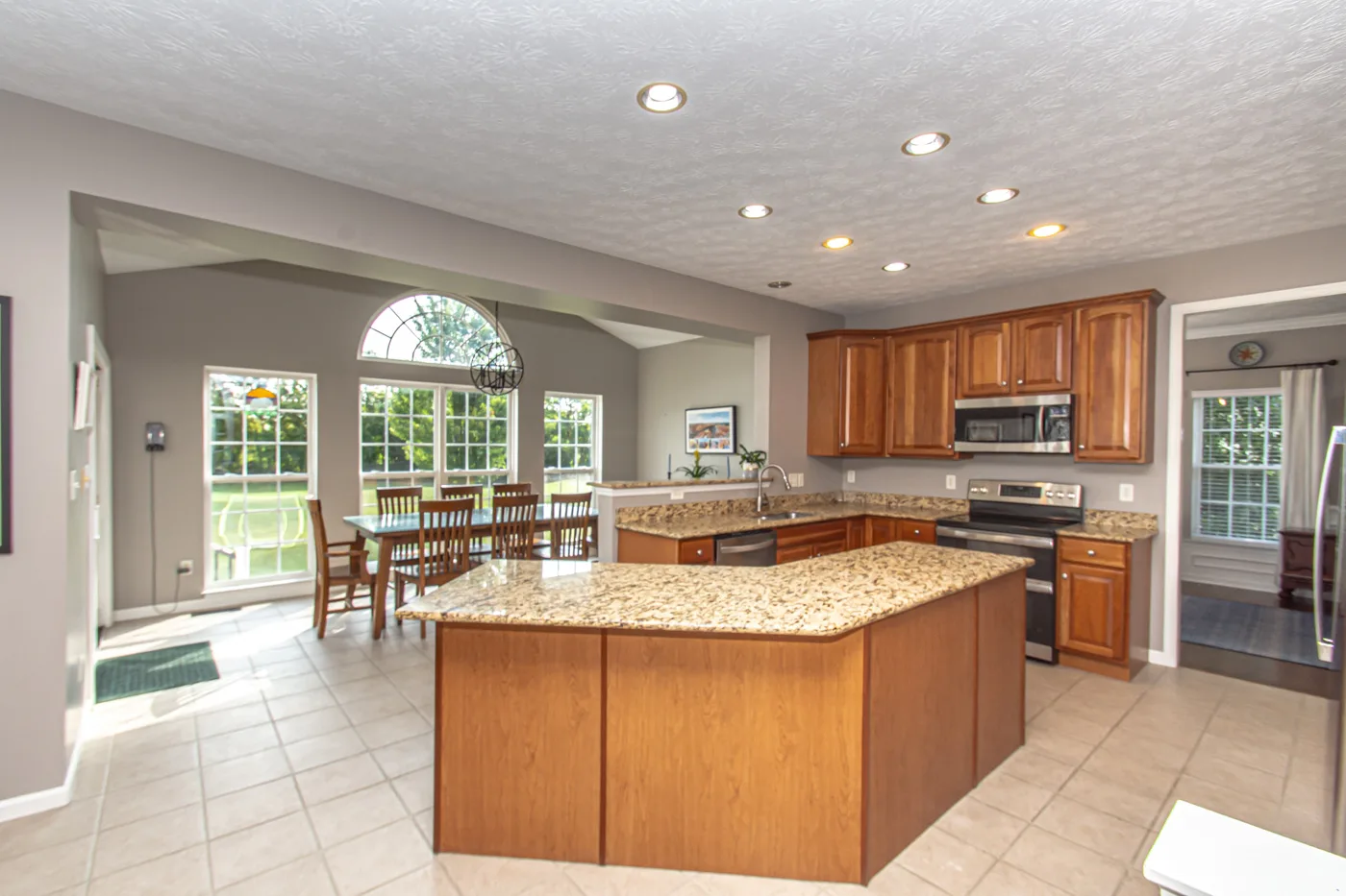 Kitchen with granite countertops, wood cabinetry, and adjoining morning room with cathedral ceiling