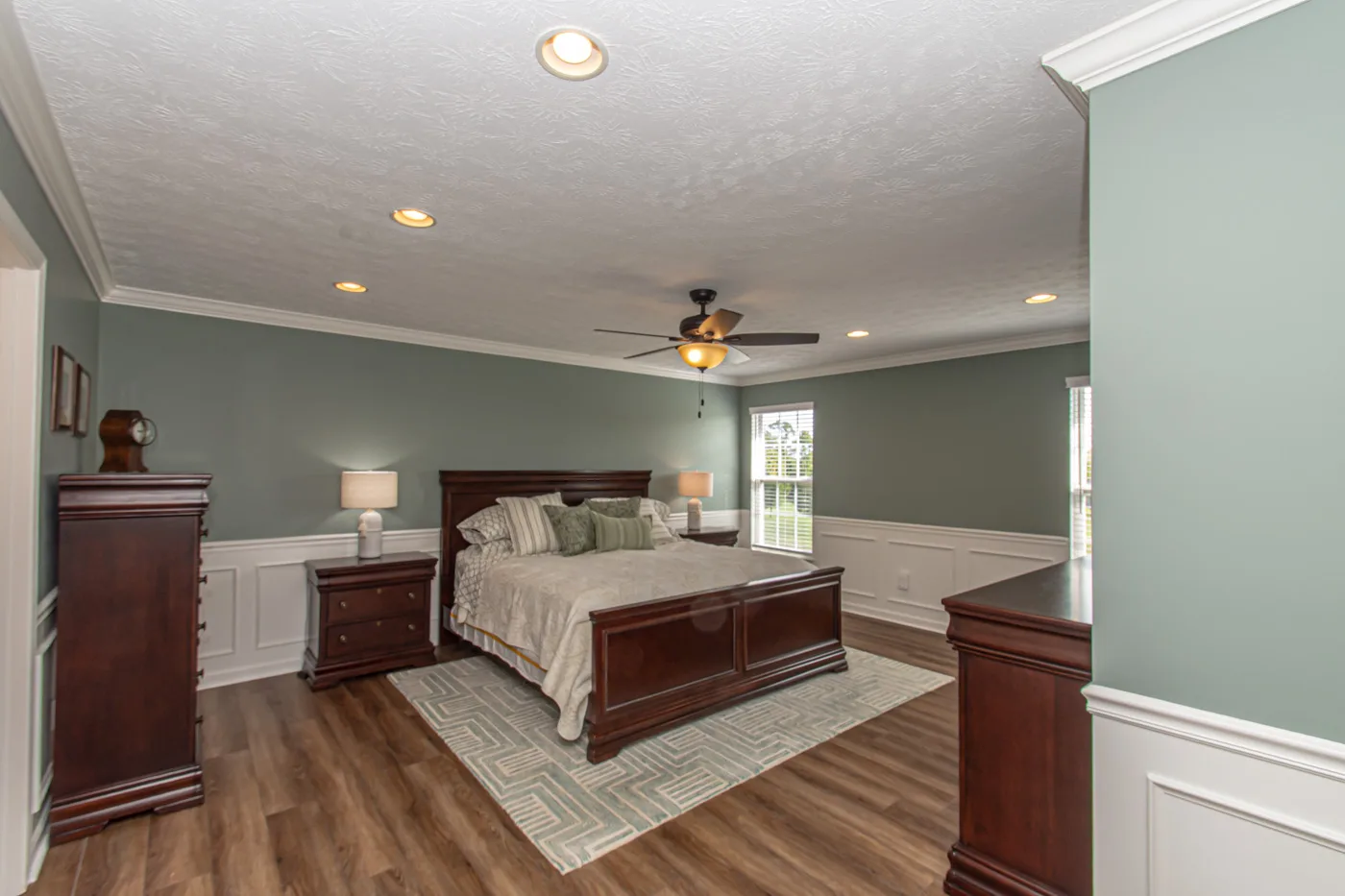 Primary bedroom suite with sage green walls and luxury vinyl plank flooring