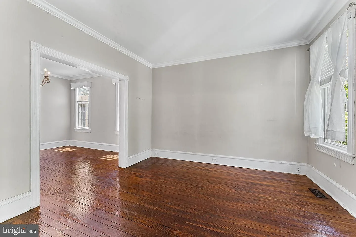 Living room with original hardwood floors, crown molding, and tall baseboards