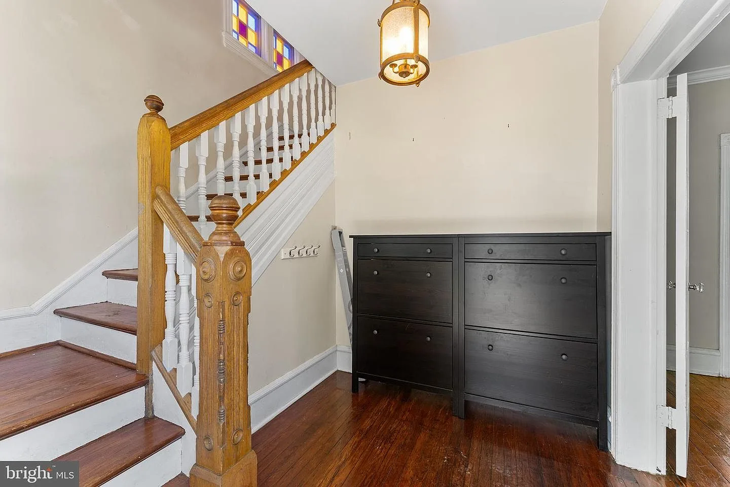 Victorian entryway with original wood staircase, stained glass transom, and hardwood floors