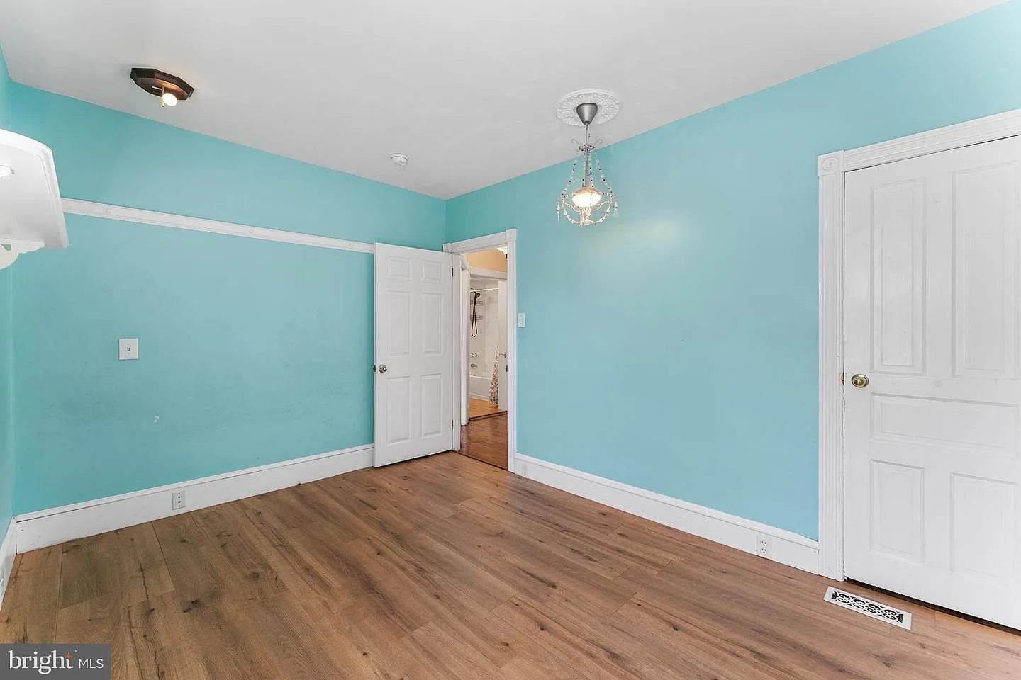 Bedroom with turquoise walls and hardwood flooring