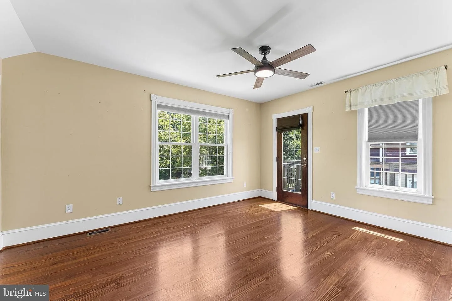 Master bedroom with neutral walls and wide-plank hardwood flooring