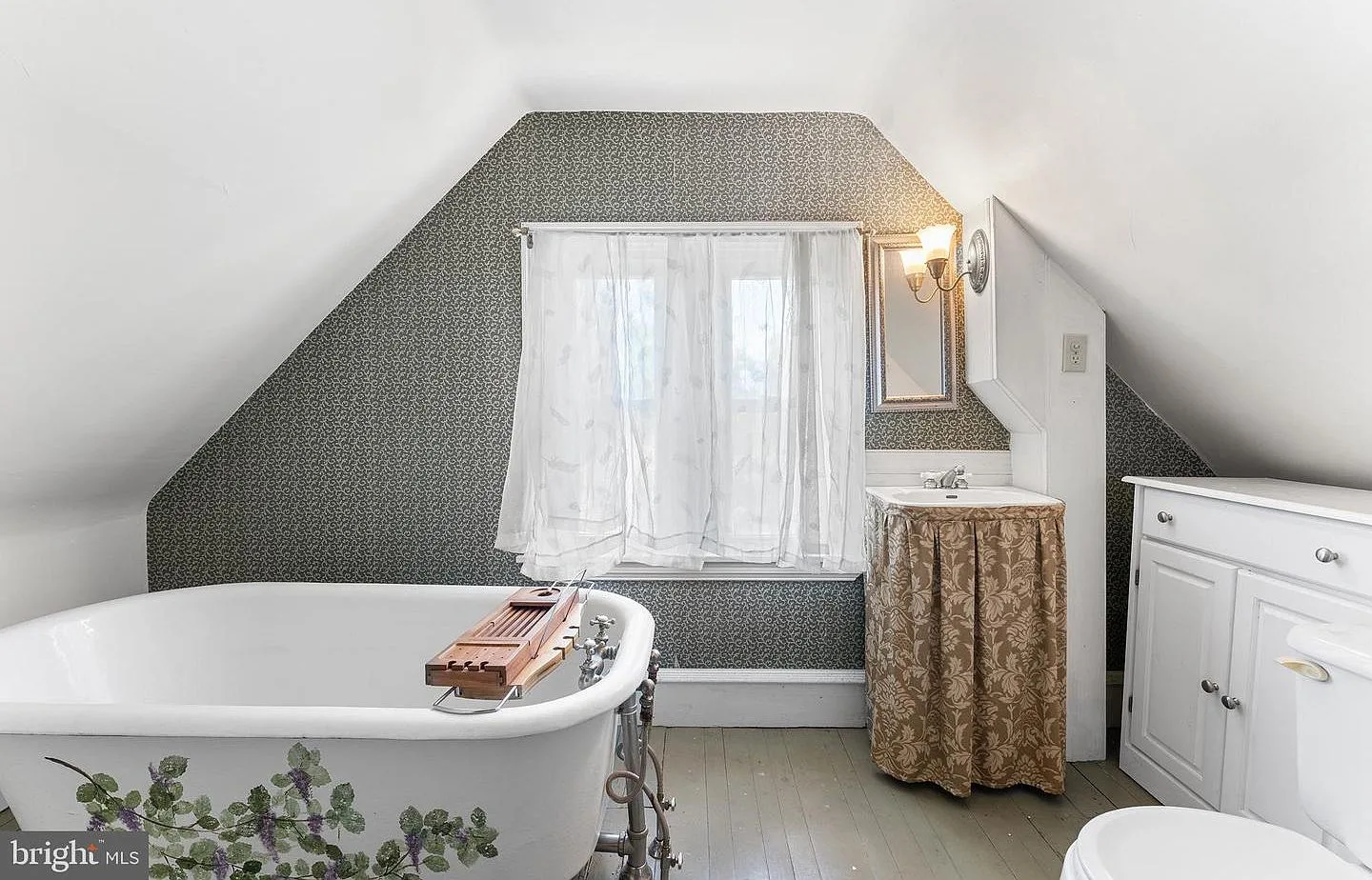 Attic bathroom with clawfoot bathtub and Victorian wallpaper