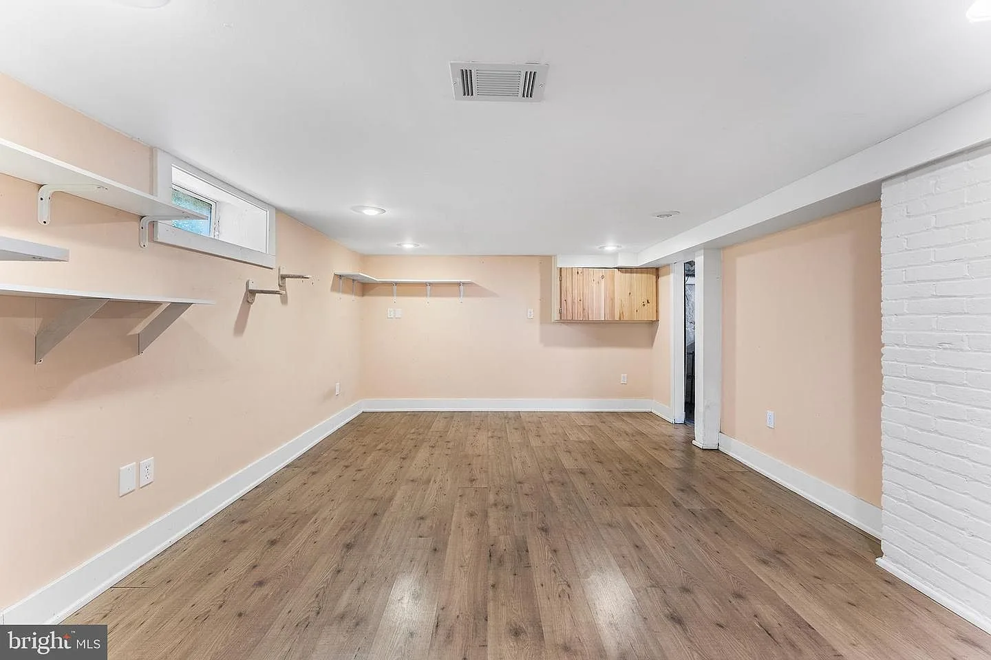 Finished basement recreation room with shelving and vinyl plank flooring