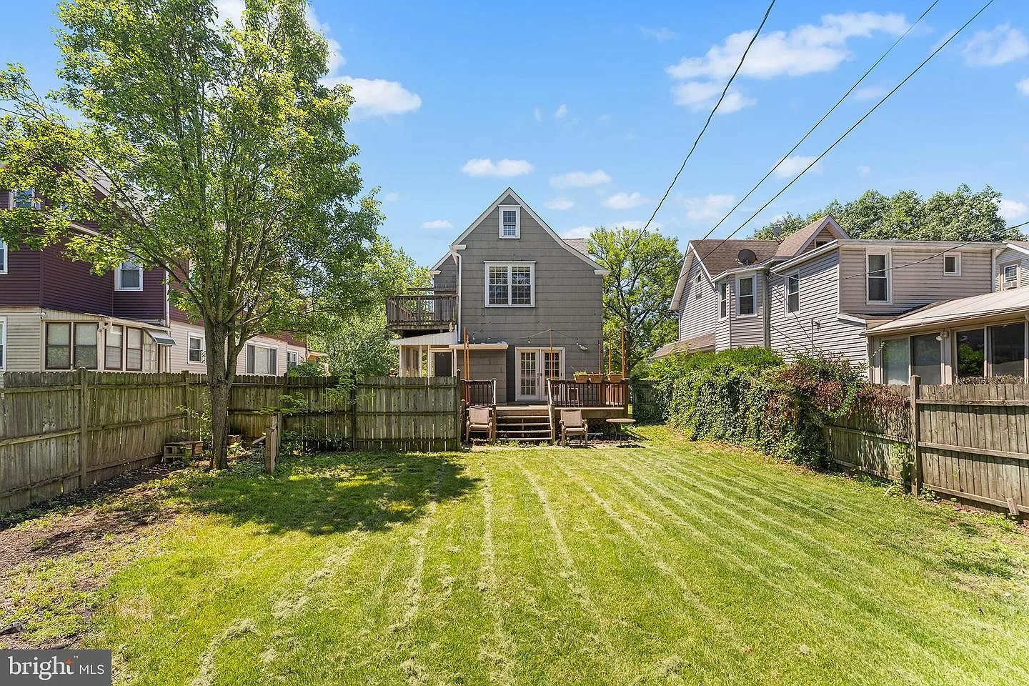 Backyard view with lawn, wooden deck, and fencing