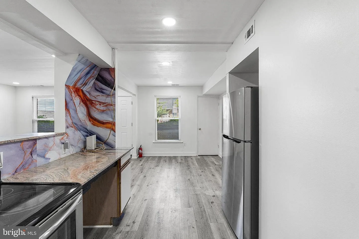 Kitchen looking through to dining area with abstract-patterned backsplash feature wall