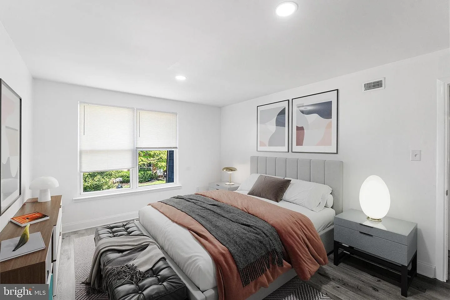 Furnished master bedroom with upholstered headboard and mid-century style furniture
