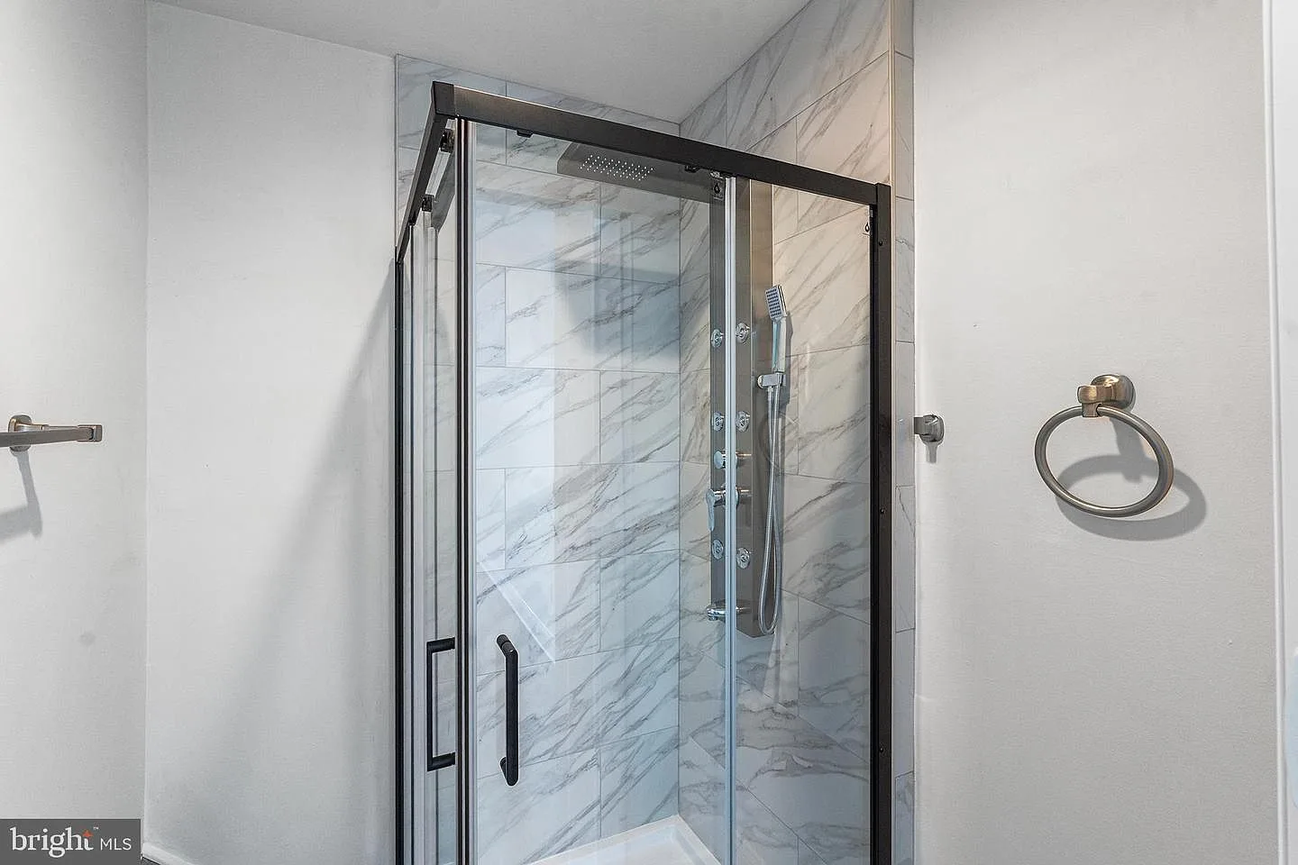 Walk-in shower with marble-look tile walls and black-framed glass enclosure