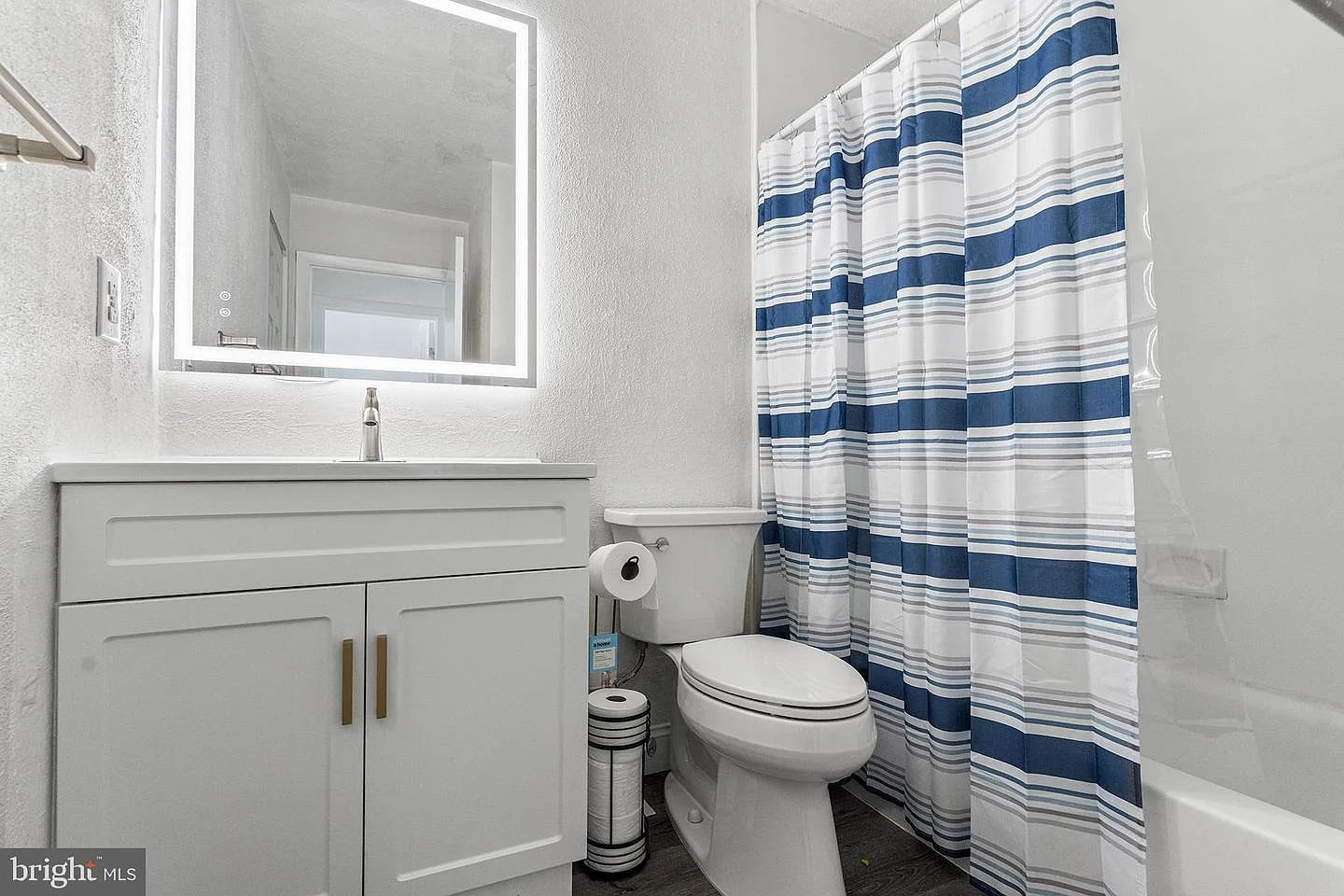 Second bathroom with white vanity, gold hardware, and backlit vanity mirror