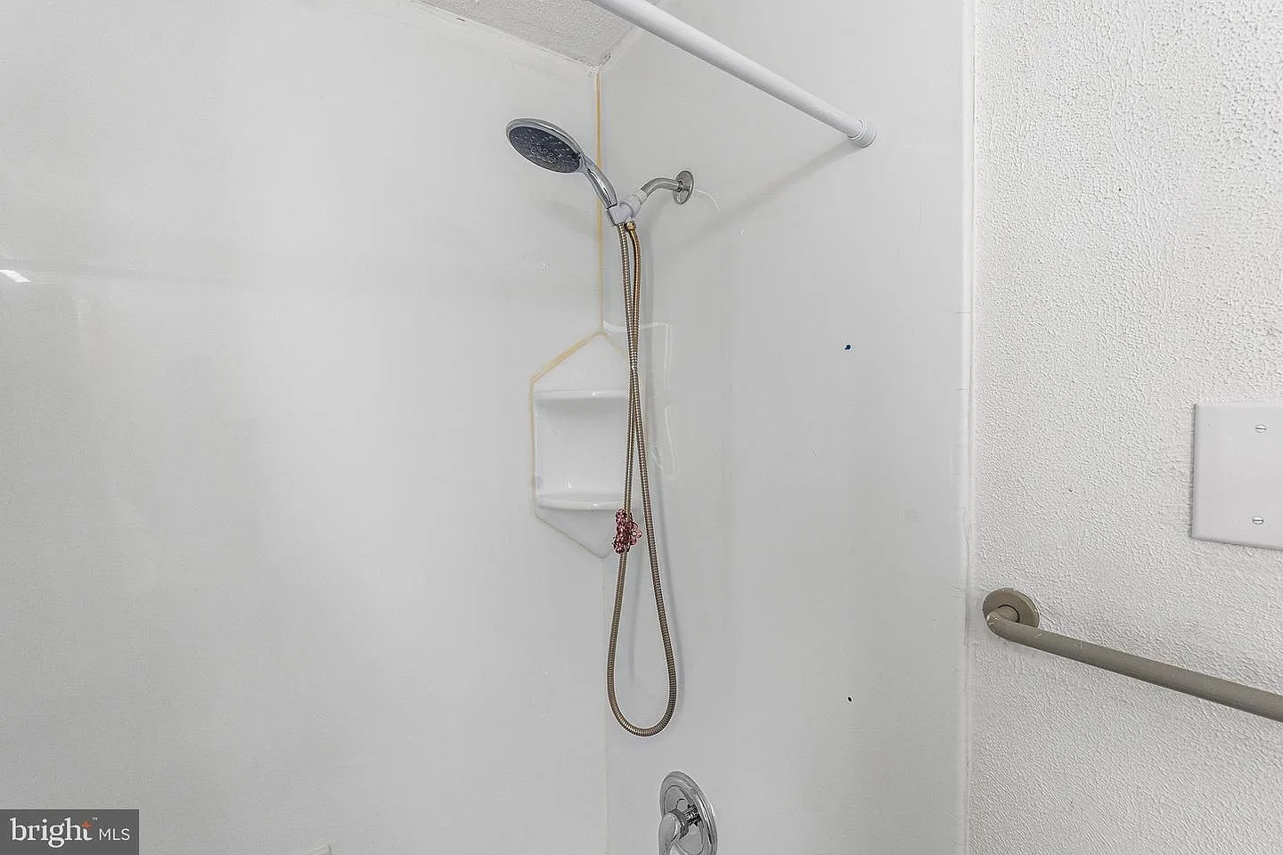 White acrylic shower surround with built-in soap niche and handheld showerhead