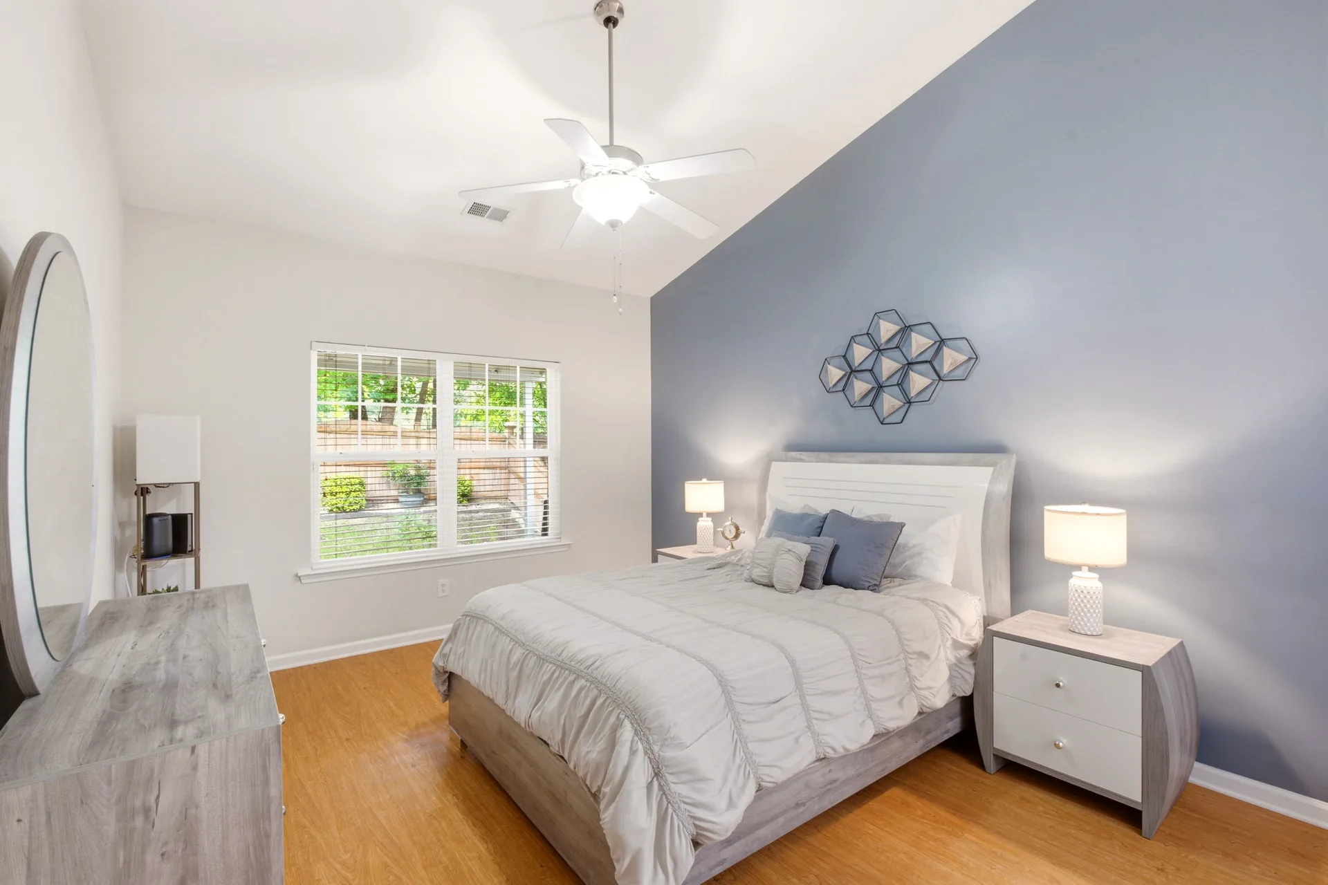 Primary suite on the main floor with blue accent wall, vaulted ceiling, and ceiling fan