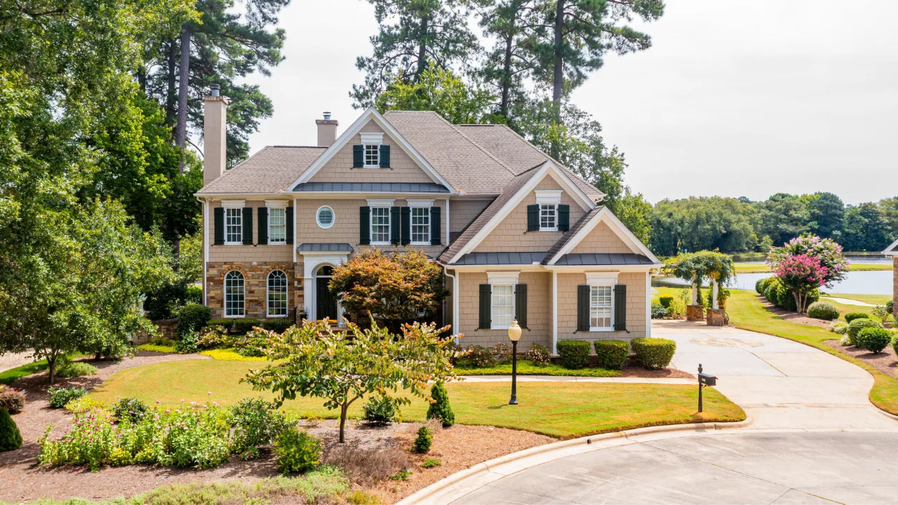 Traditional coastal-style home with tan siding, stone accents, and green shutters in Cary, NC