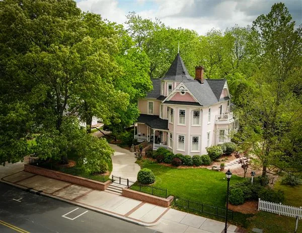 Victorian-style home with pink siding, turreted roofline, and wrap-around porch in downtown Cary, NC