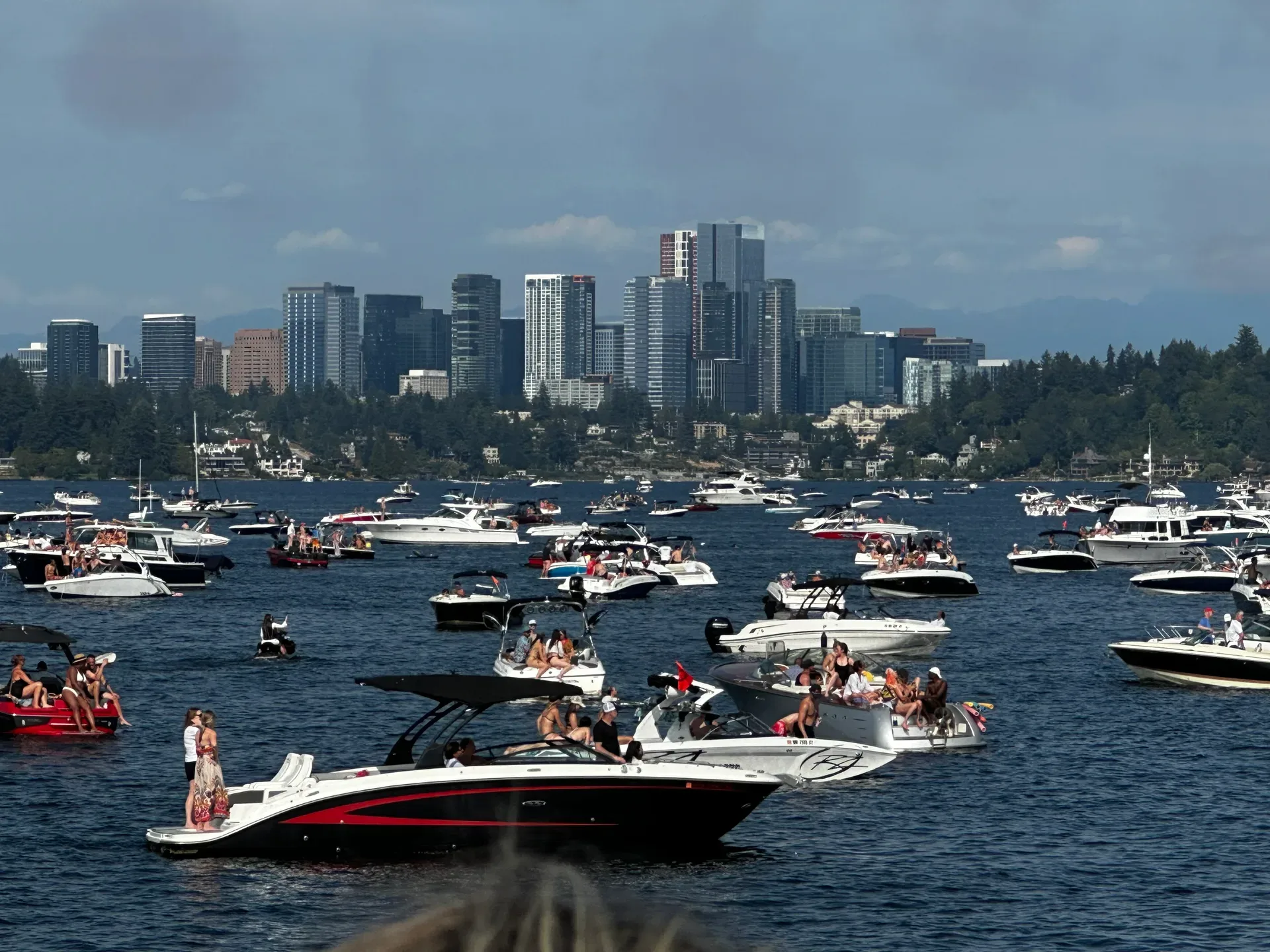 Boats packed on Lake Washington during Seafair weekend with the Bellevue skyline rising in the background under a bright blue sky