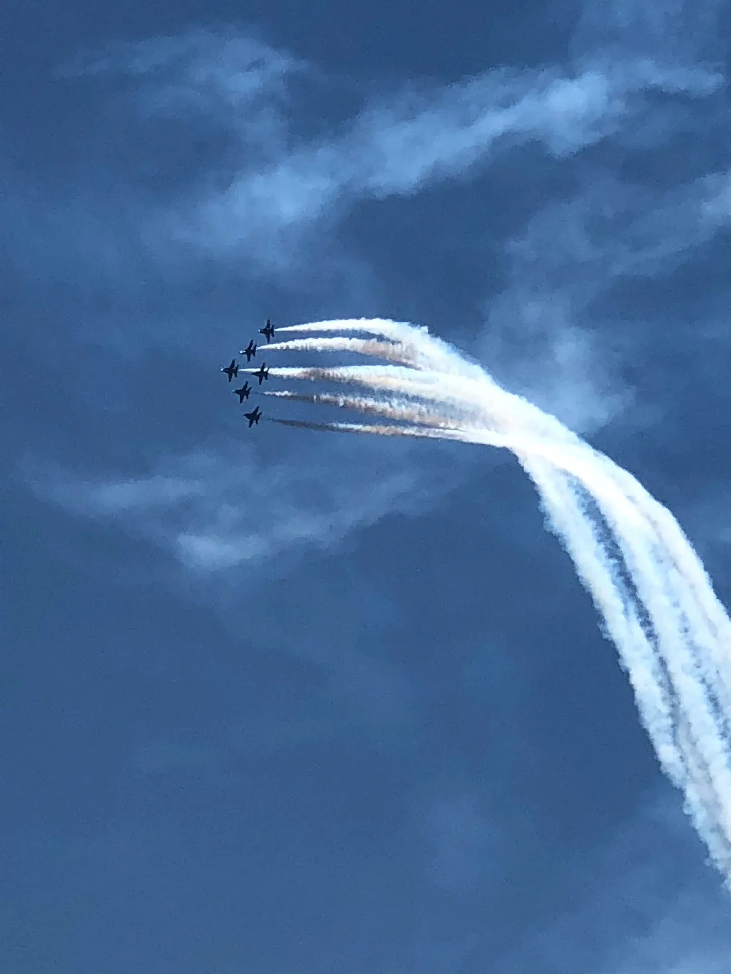 Blue Angels jets in tight formation leaving smoke trails across a bright blue sky with wispy clouds during Seafair weekend