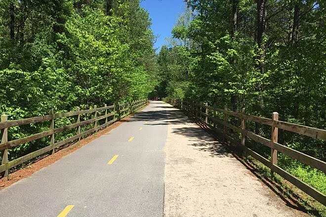 Paved recreational trail with wood fence lining the American Tobacco Trail corridor in Cary, NC