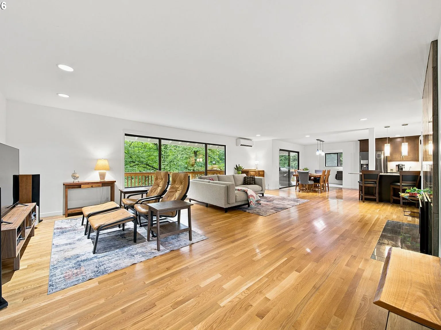 Open-concept living area with hardwood floors and forest views through large windows