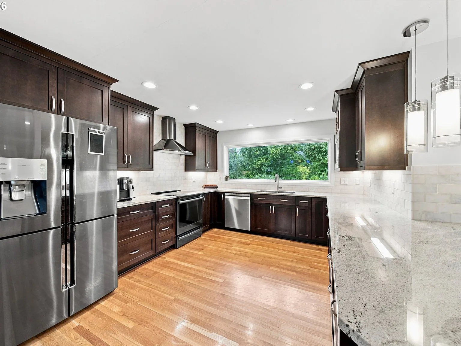 Remodeled modern kitchen with dark espresso cabinetry, marble-style countertops, and stainless steel appliances
